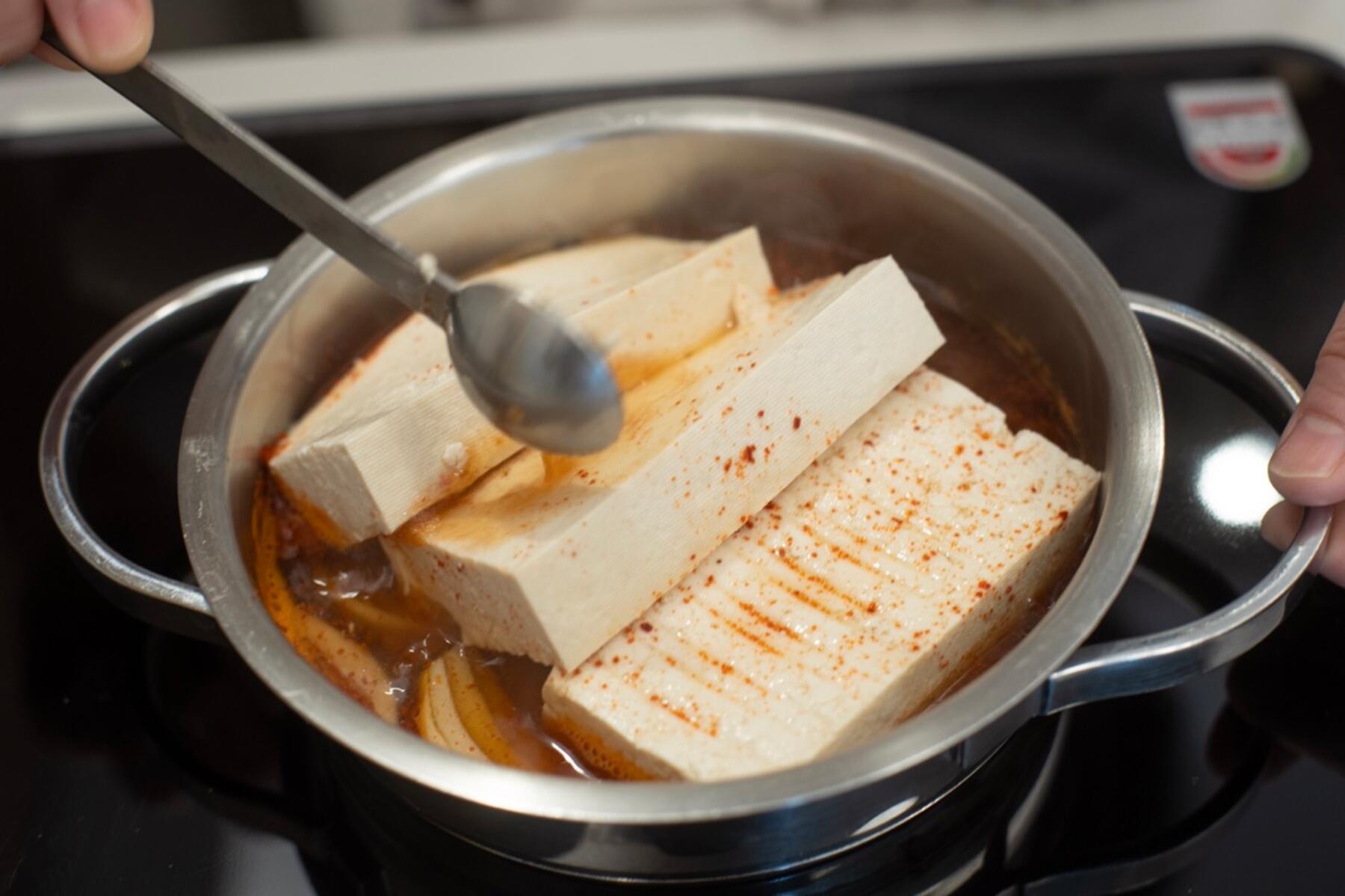 煮汁をかけながら、豆腐を煮る