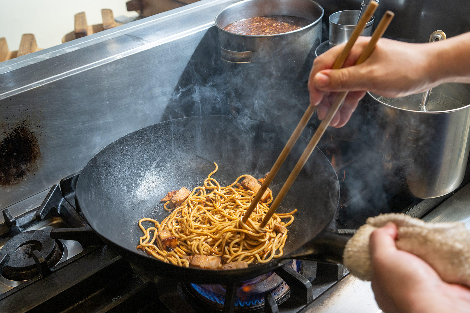 ソースと煮豚の脂を麺に絡ませる
