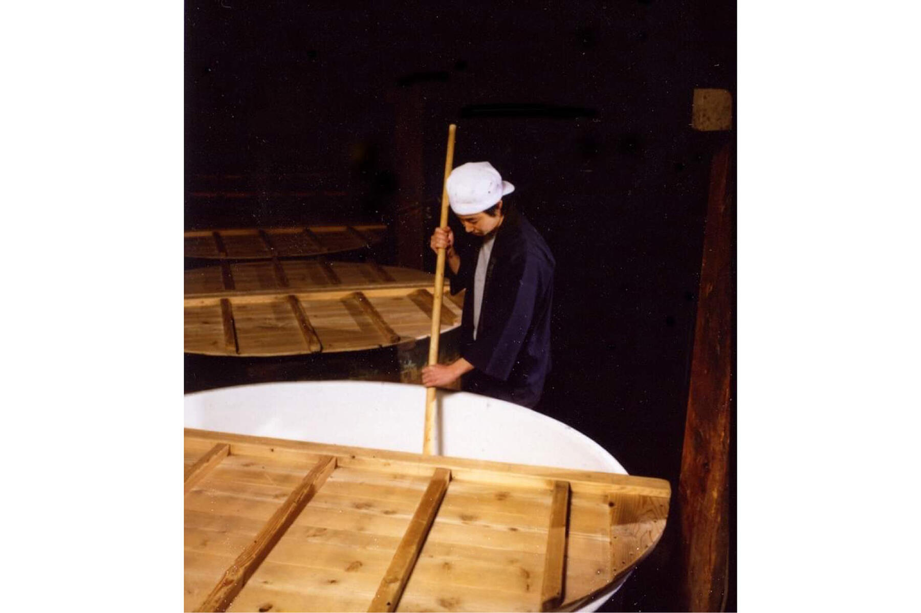 ホウロウ製仕込みタンクに櫂を入れる大西さん