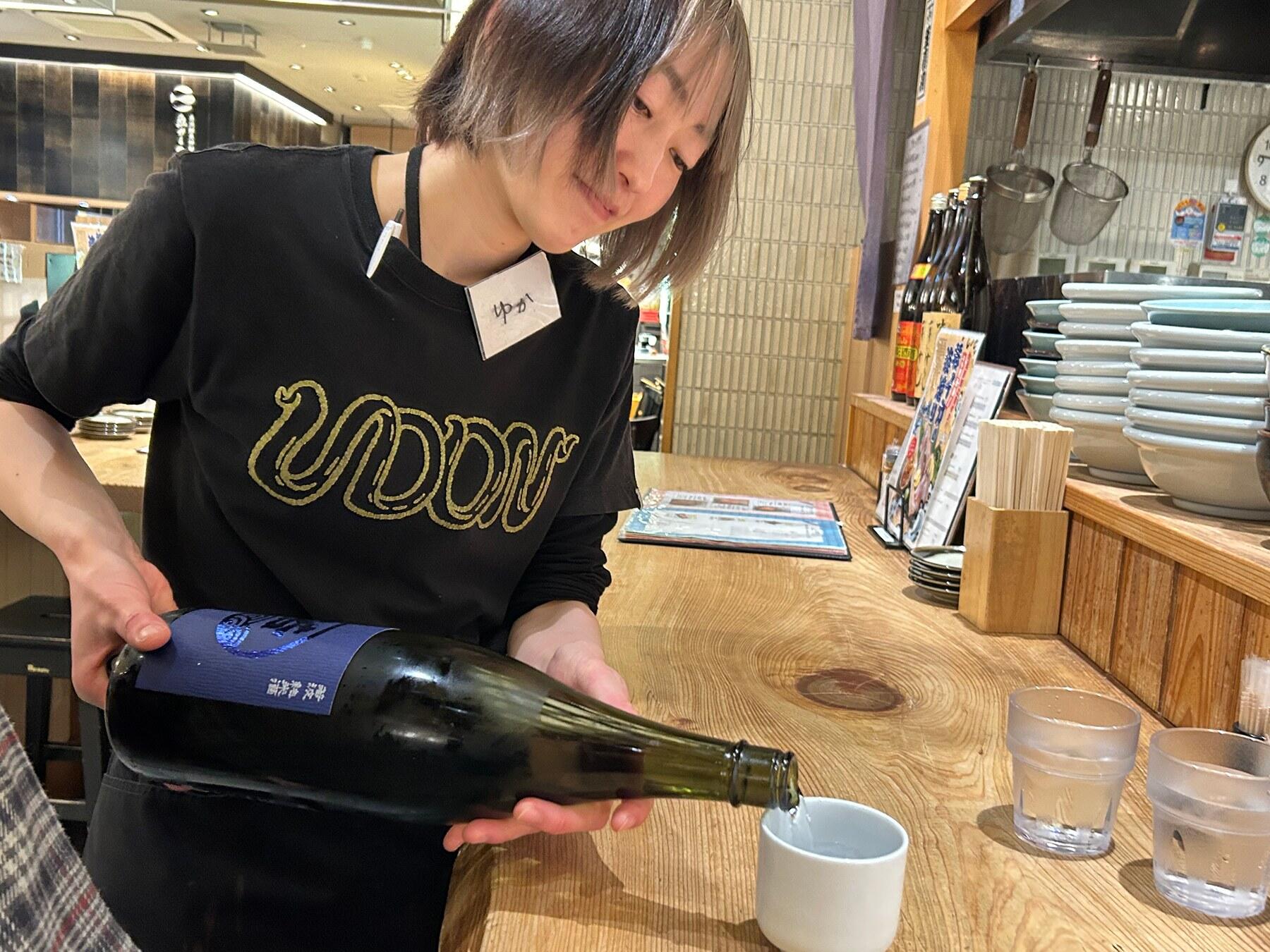 日本酒をつぐスタッフ