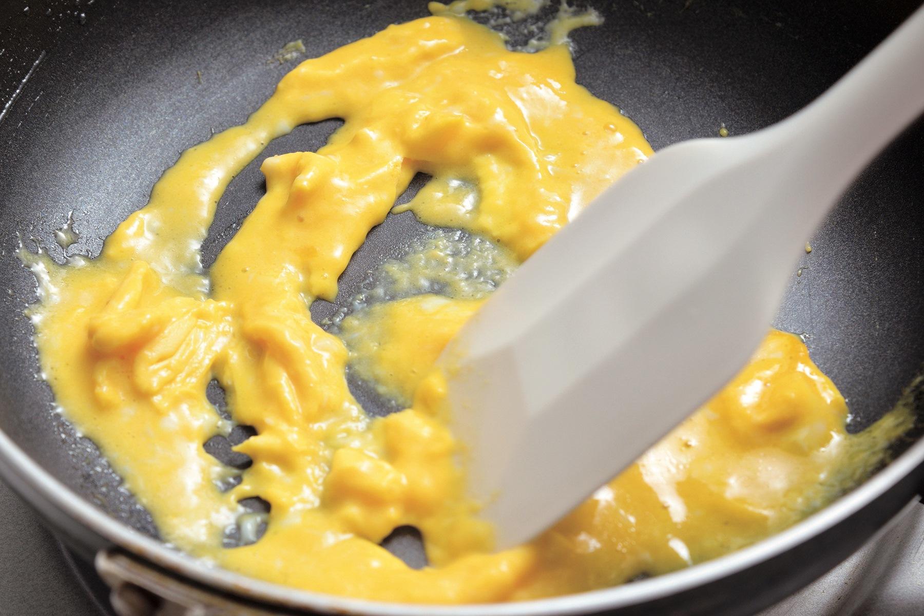 卵が固まってきたら、底からはがすようにヘラで混ぜる。