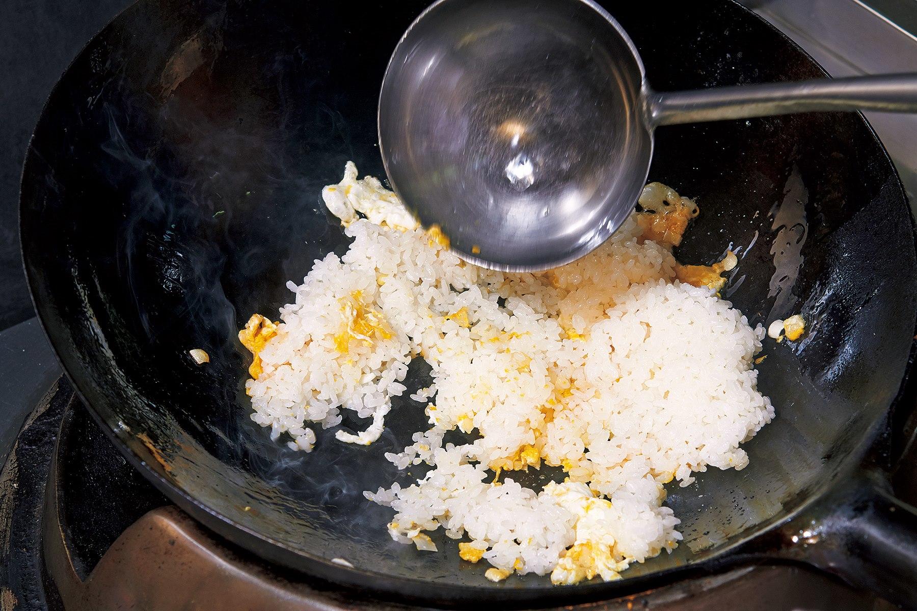 お玉の背でつぶすようにしながらごはんをほぐす。