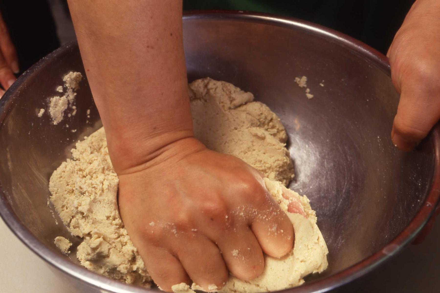 指先で粉をまき込むように混ぜ、まとまってきたら手首で押さえつけるようにして練る。
