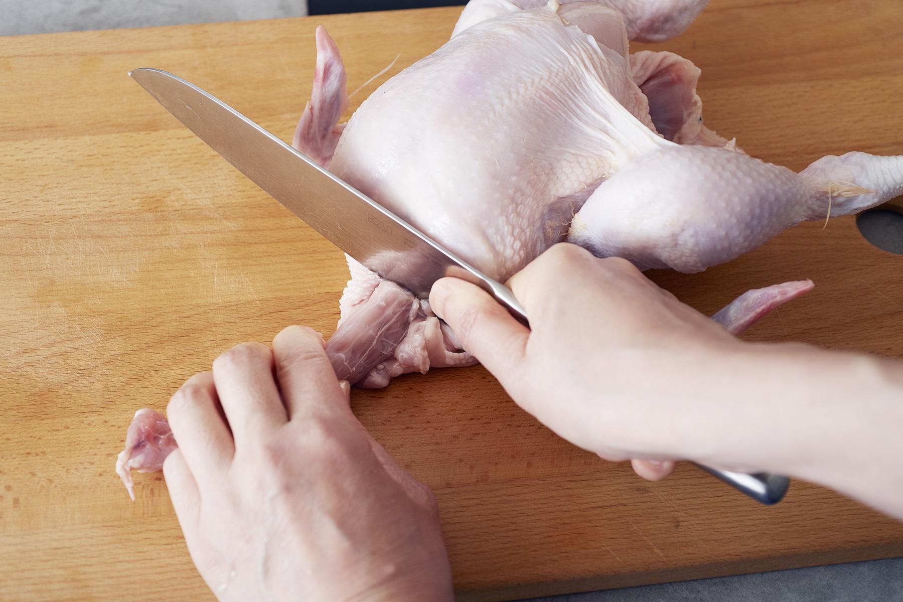 首の付け根にある骨のくぼみに包丁の根元をあて、押し込むようにして切る。