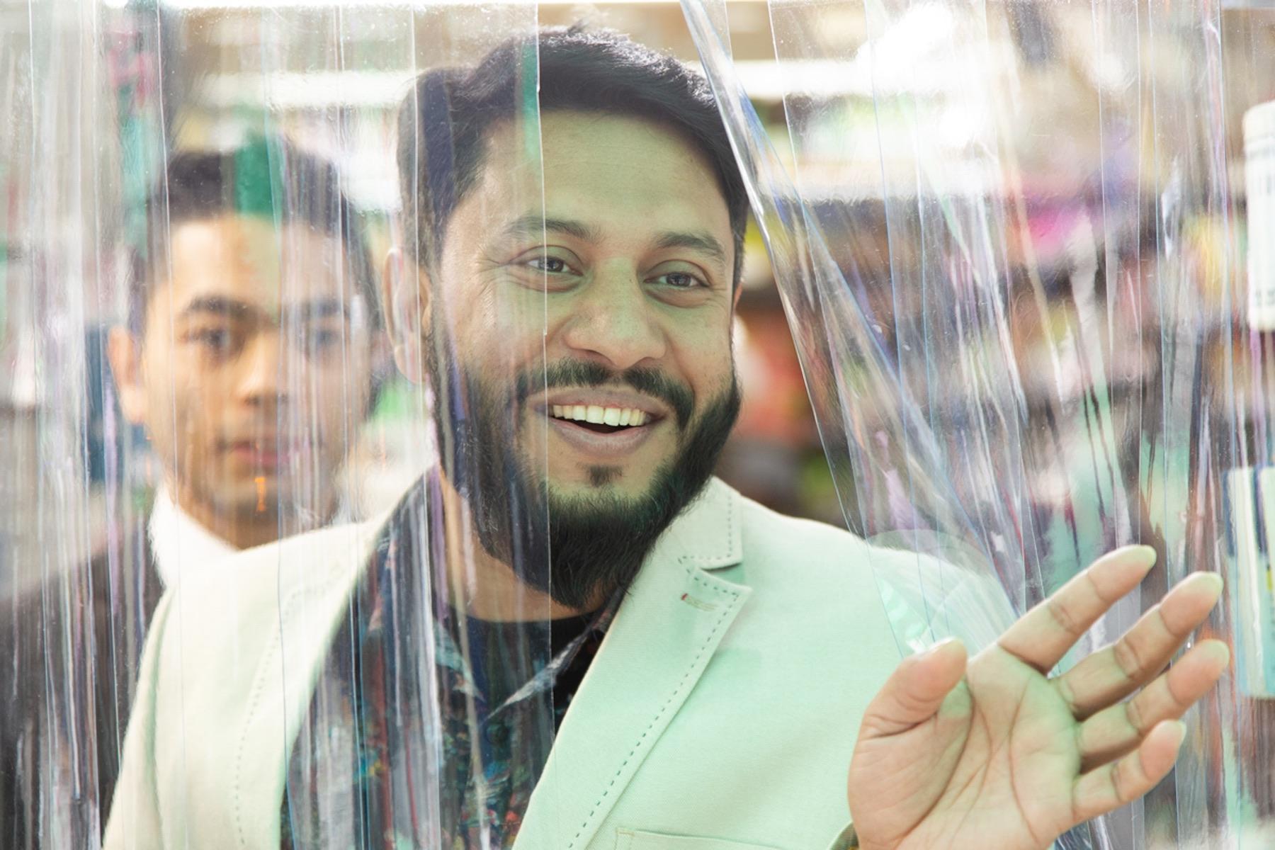 ビニールカーテン越しに常連さんと談笑する「ジャンナット ハラルフード」のオーナー。カーテンは暖房対策と思われます。