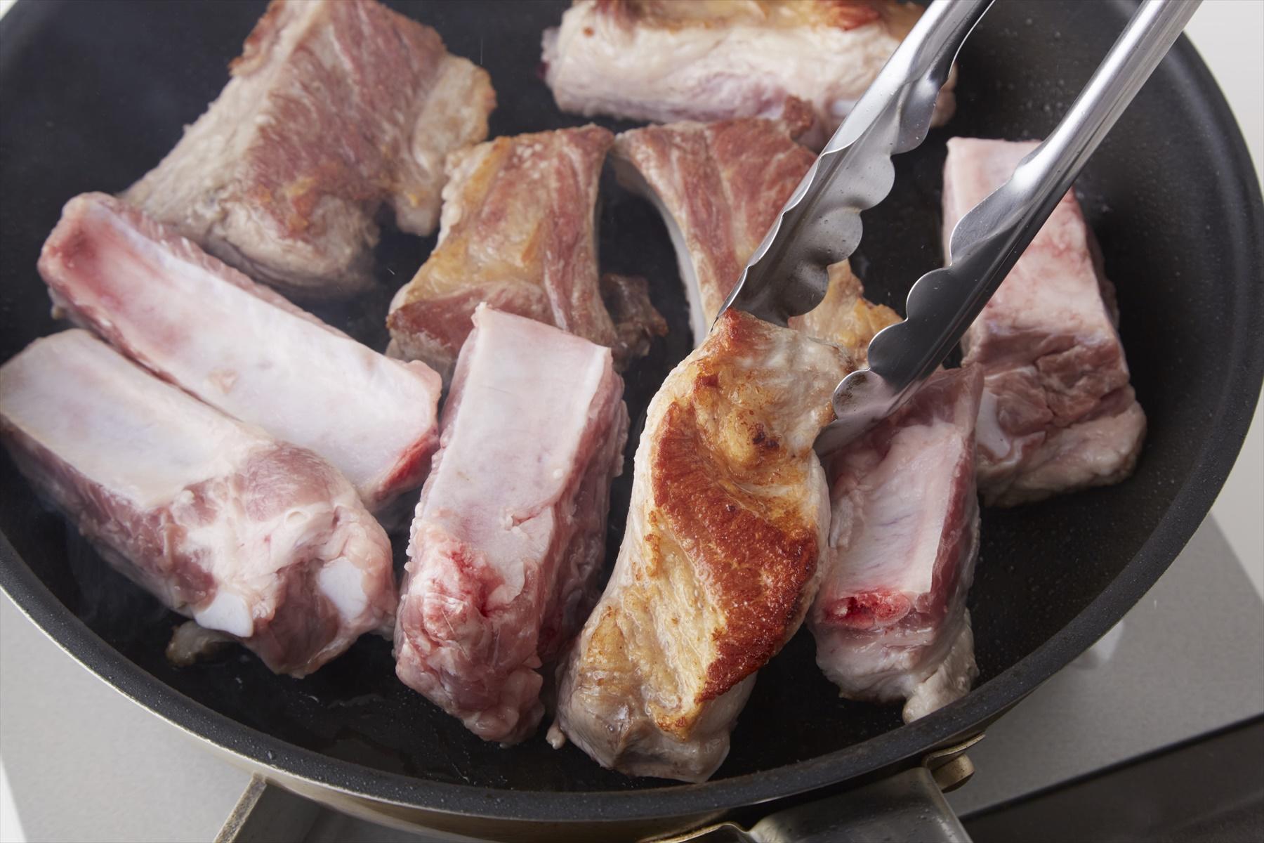 スペアリブの表面をこんがりと焼きつけると、肉の臭みが消えて香ばしくなる。途中、余分の脂をペーパーで拭き取りながら作業して。