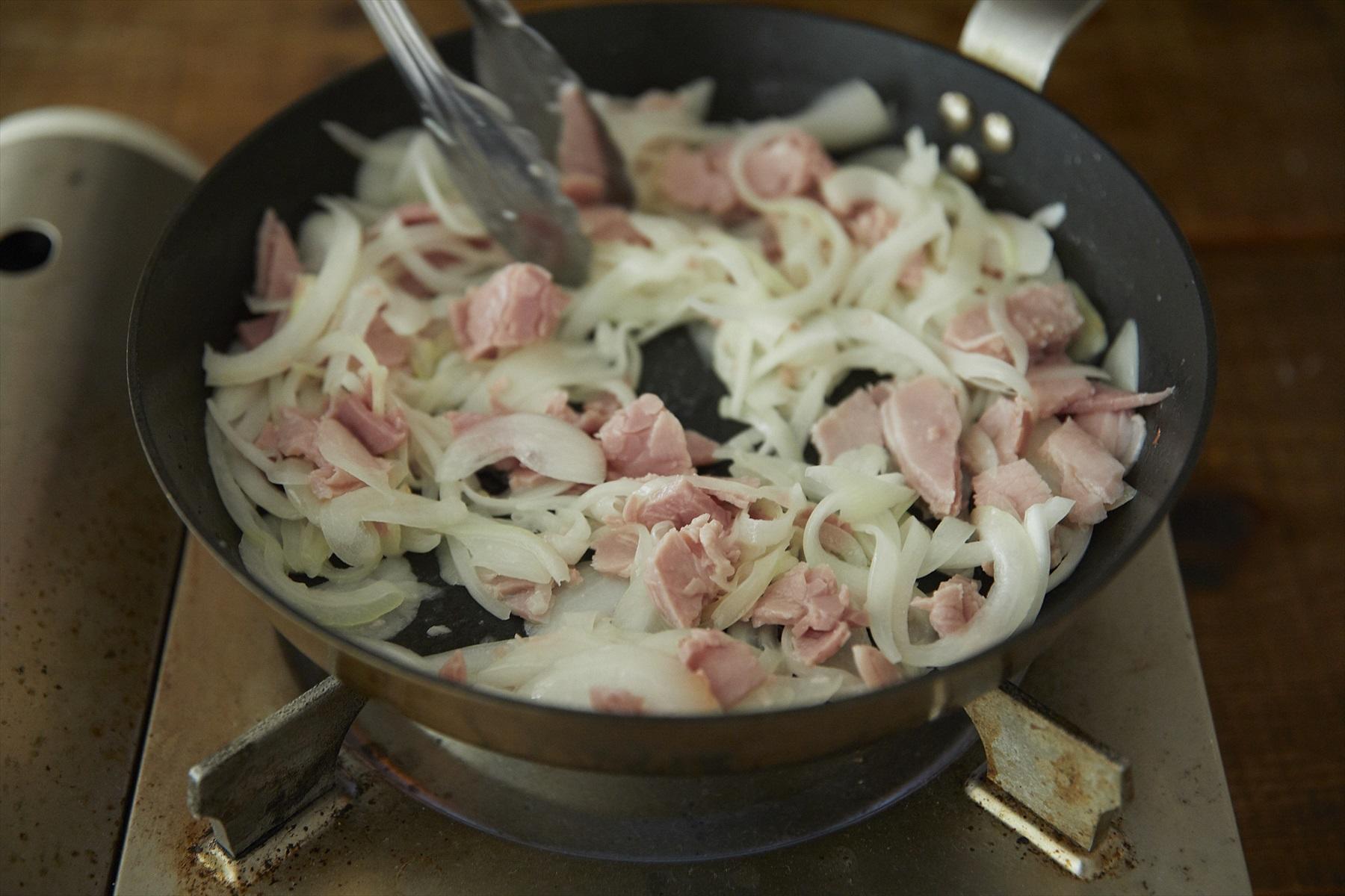 玉ねぎはうす切りにして、ハムと共に水分が出るまでフライパンでソテーする