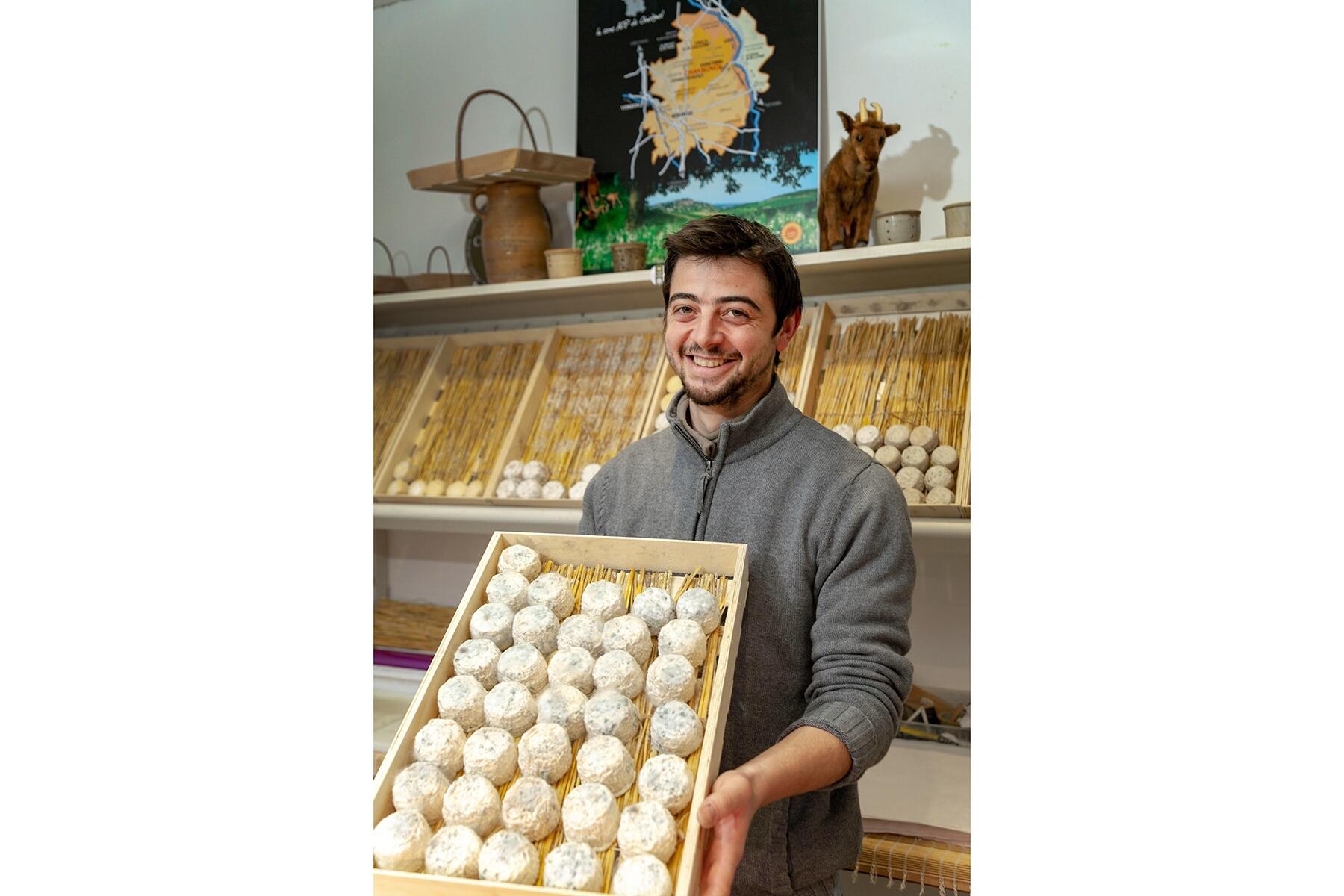 チーズの並んだ箱を持つ男性