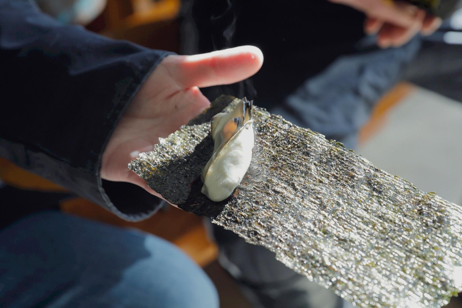 蒸し牡蠣の磯辺巻きを持つ手