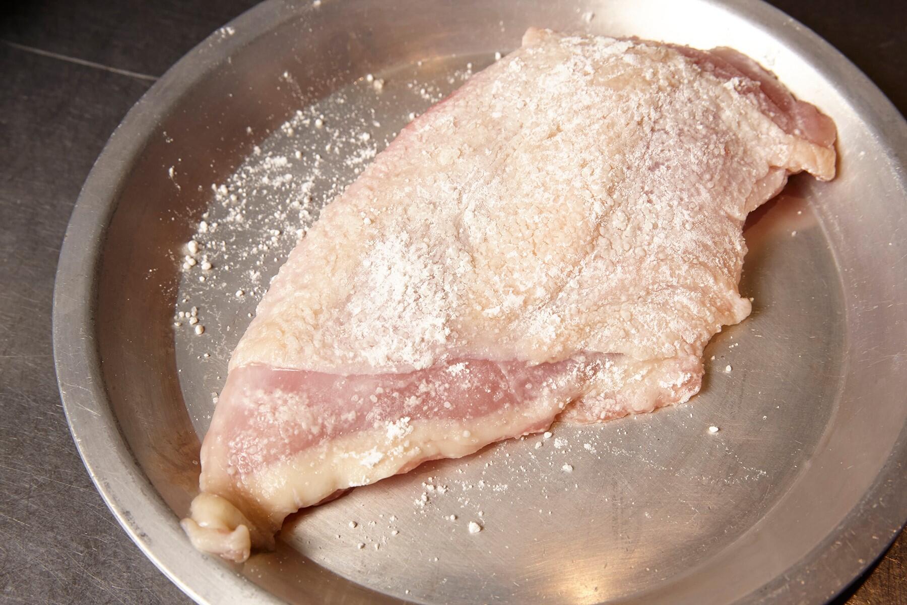 鶏肉に小麦粉をはたく