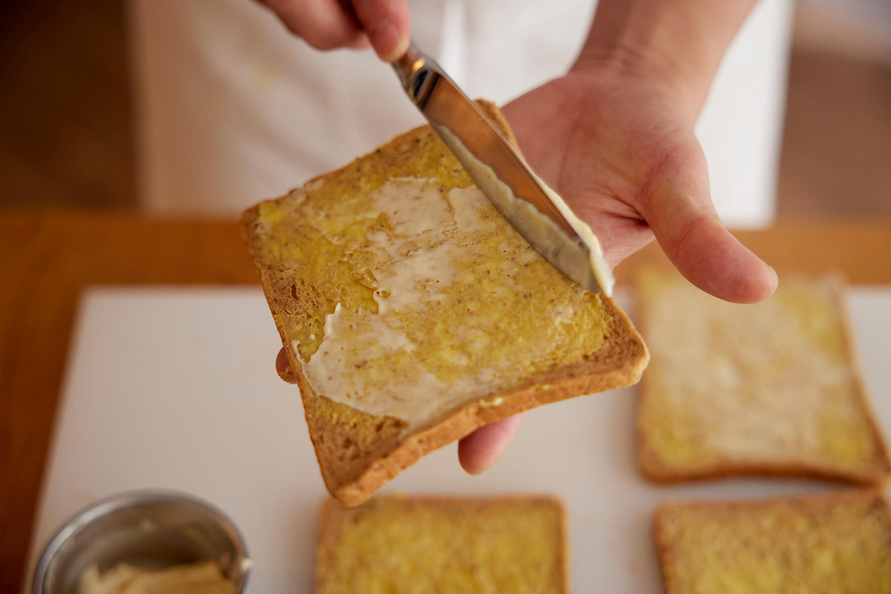 パンにからしバターとマヨネーズを塗る