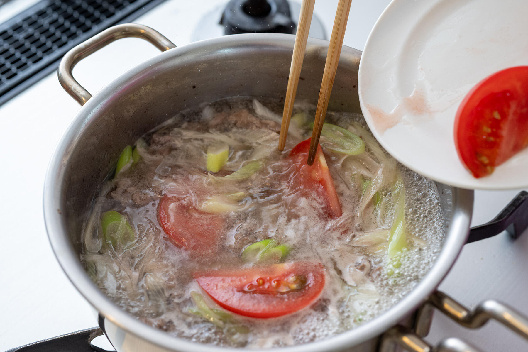 トマトを加えて味つけする