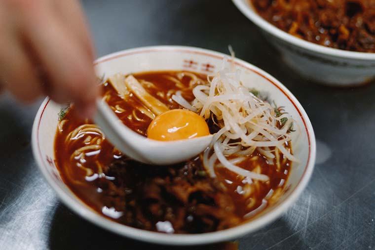 ラーメンに卵の黄身を載せているところ。